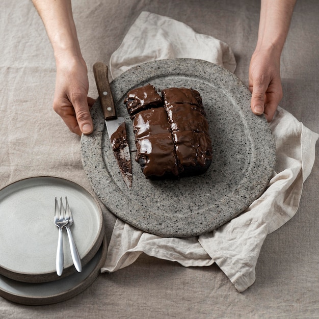 Alto ángulo de tarta de chocolate en placa sostenida por pastelero