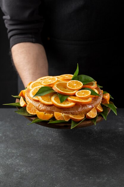 Alto ángulo de tarta de naranja celebrada por pastelero