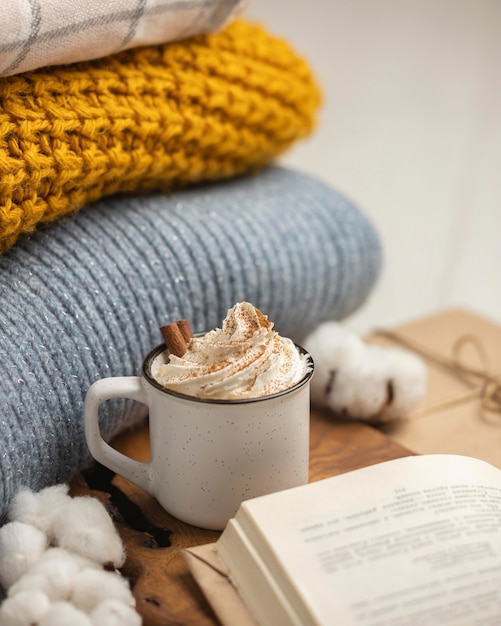 Alto ángulo de taza de café con crema batida y canela en rama