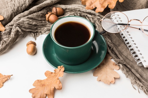 Alto ángulo de la taza de café con hojas de otoño y bellotas