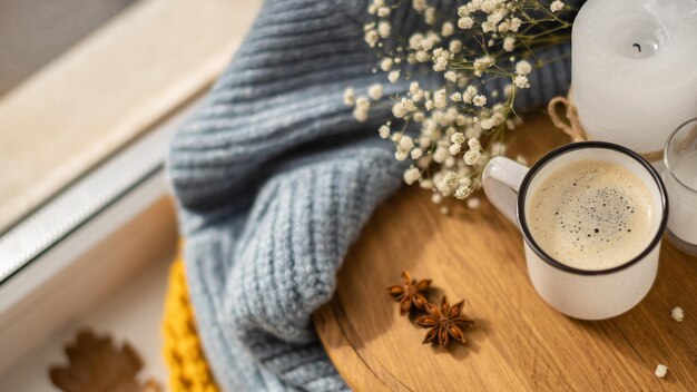 Alto ángulo de taza de café con suéter y hojas de otoño
