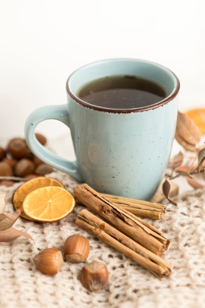 Alto ángulo de taza de té con castañas y ramas de canela