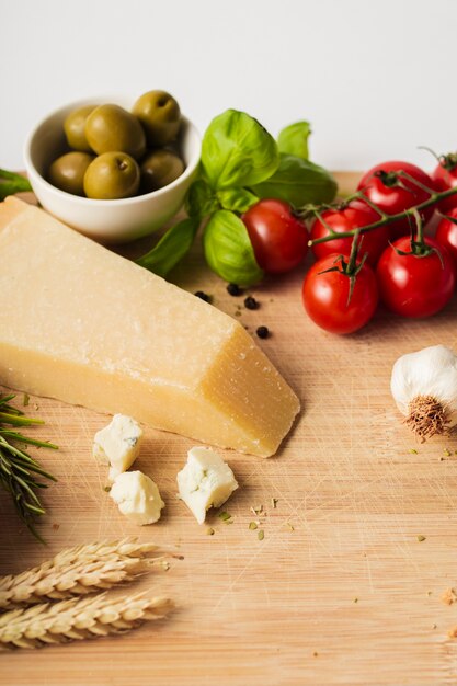 Alto ángulo de tomates parmesanos y ajo en tabla de cortar