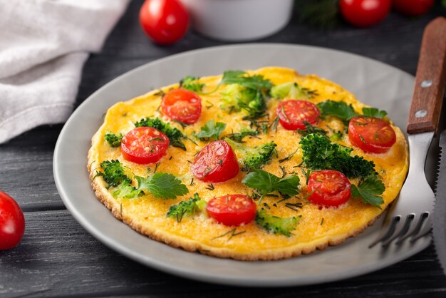 Alto ángulo de tortilla para el desayuno con tomates y hierbas.