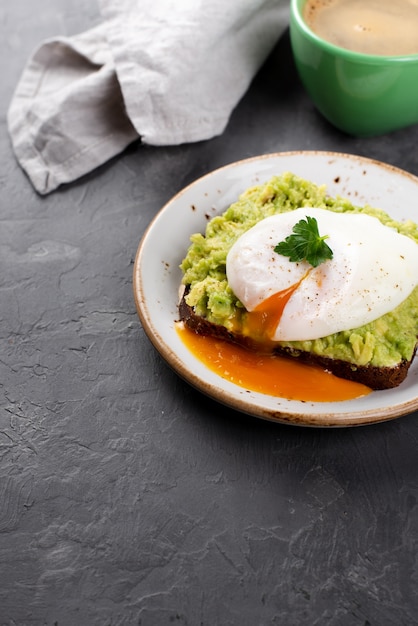 Alto ángulo de tostadas de aguacate con huevo escalfado y taza de café