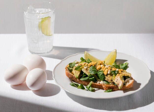 Alto ángulo de tostadas de aguacate en un plato con un vaso de agua helada y huevos