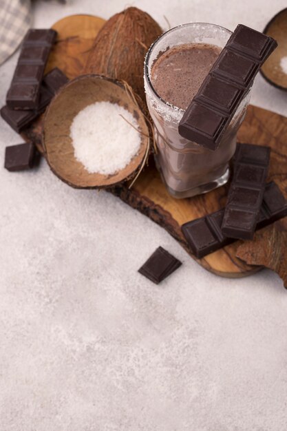 Alto ángulo de vaso de batido de chocolate y coco con espacio de copia