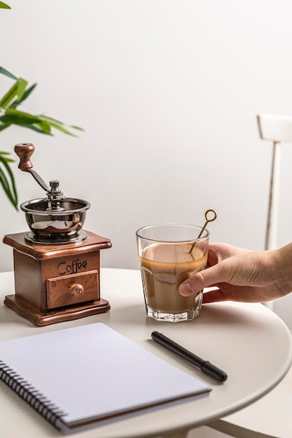 Alto ángulo de vaso de café con molinillo y portátil en la mesa