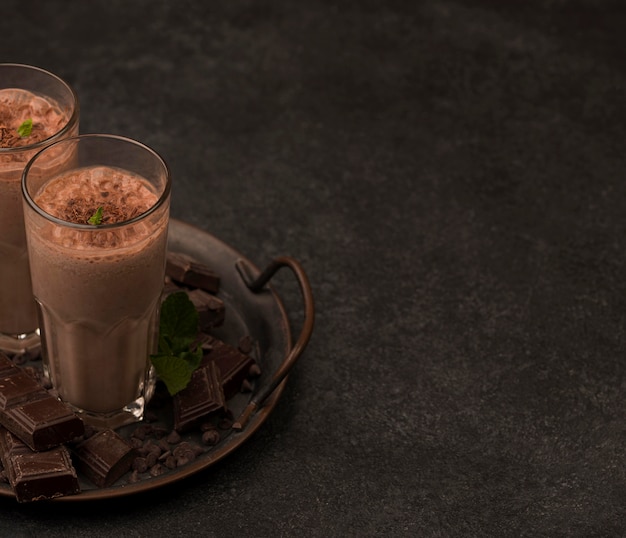 Foto gratuita alto ángulo de vasos de batido en bandeja con chocolate y copie el espacio