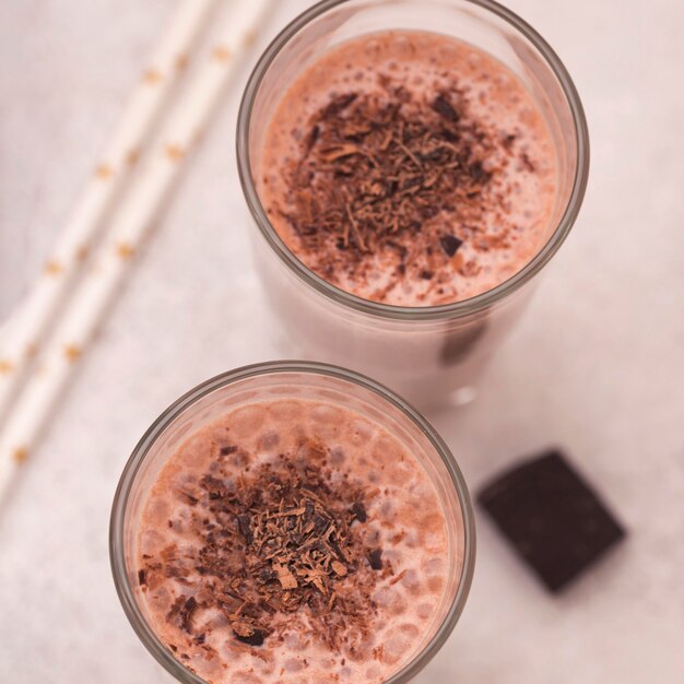 Alto ángulo de vasos de batido con chocolate y pajitas