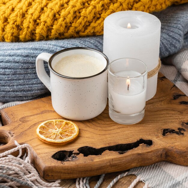 Alto ángulo de velas encendidas con suéter y taza de café