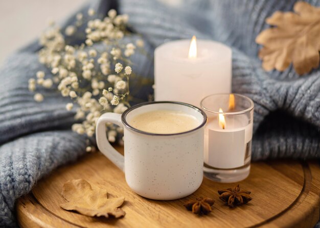 Alto ángulo de velas encendidas con taza de café y suéter