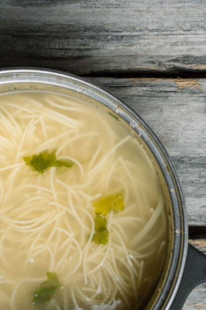 Alto ángulo vertical una sopa casera con espagueti y verduras sobre una superficie de madera