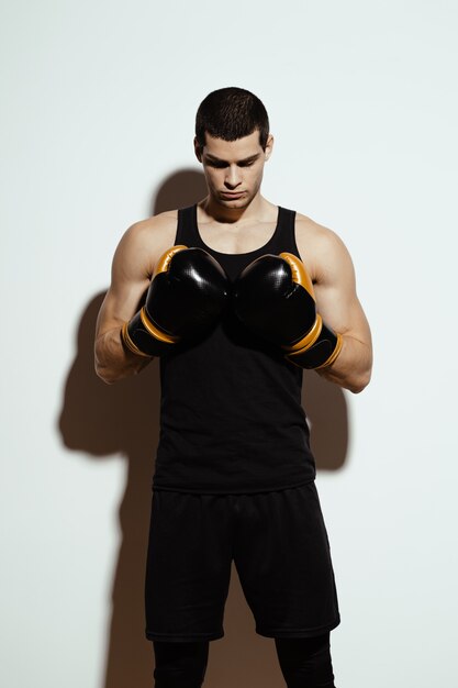 Alto deportista atractivo posando en guantes de boxeo