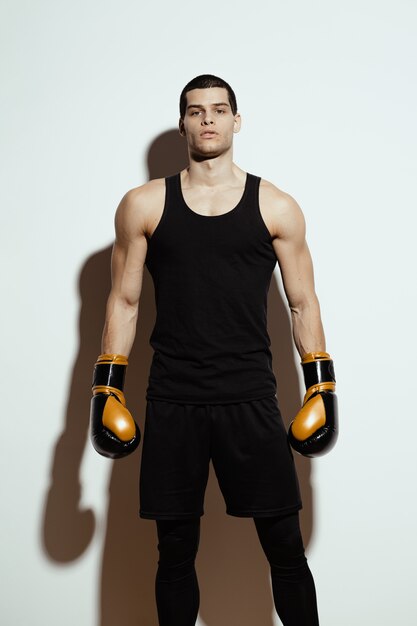 Alto deportista atractivo posando en guantes de boxeo