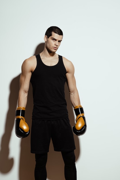 Foto gratuita alto deportista atractivo posando en guantes de boxeo