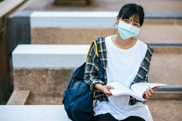 Alumnas con máscaras y libros en las escaleras.