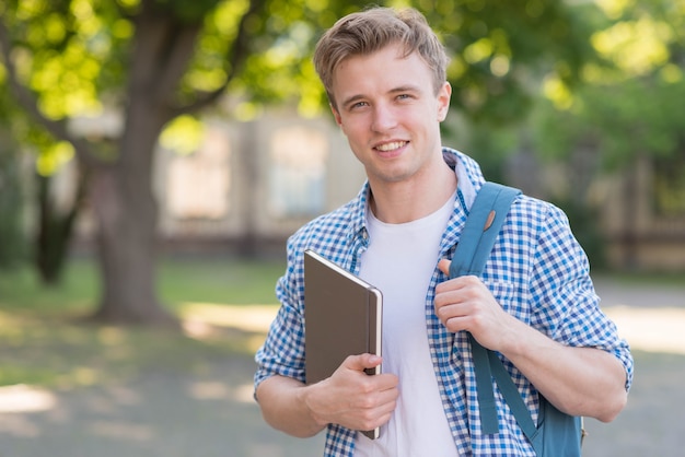 Foto gratuita alumno con libro en el parque