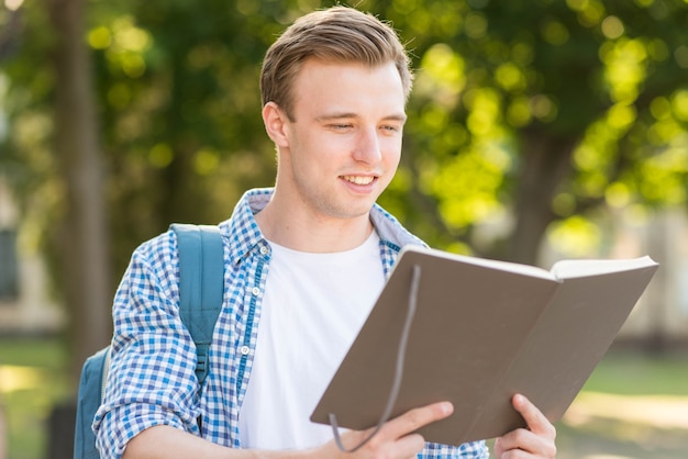 Foto gratuita alumno con libro en el parque