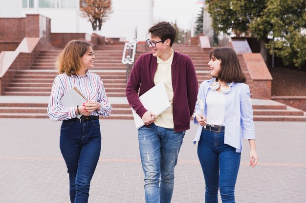 Alumnos adolescentes caminando con libros y hablando de lecciones.