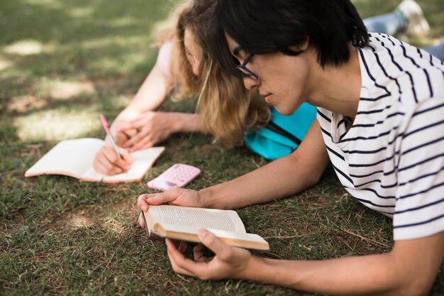 Alumnos multirraciales con libros sobre hierba verde.
