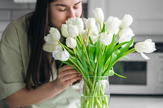 Foto gratuita ama de casa disfrutando de un ramo de flores en el interior de la cocina