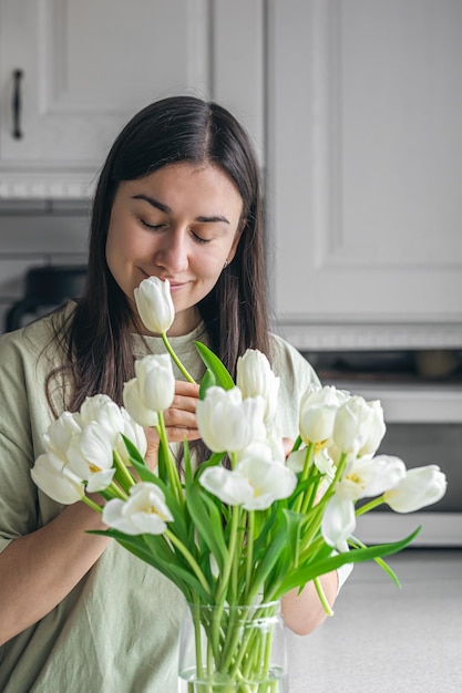 Ama de casa disfrutando de un ramo de flores en el interior de la cocina