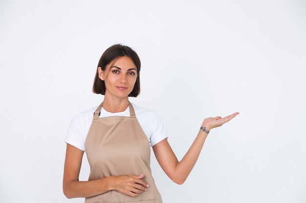 Ama de casa feliz en delantal aislado en blanco mantenga la mano derecha con espacio vacío