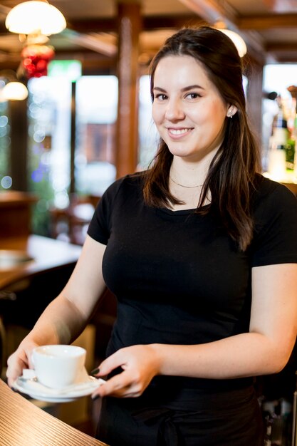 Amable camarera con una taza de bebida caliente