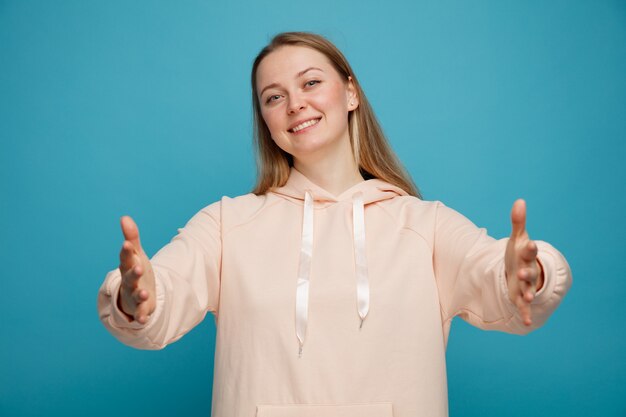 Amable joven rubia haciendo gesto de bienvenida