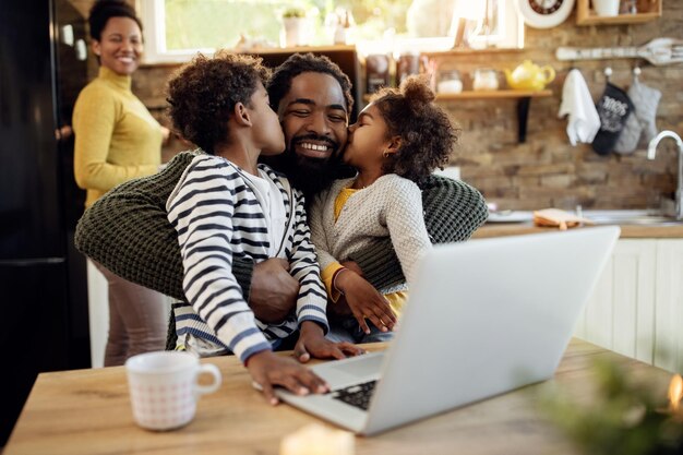 Amando a los niños afroamericanos besando a su padre en casa