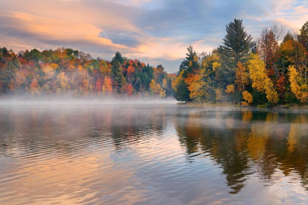 Amanecer en la niebla del lago con follaje otoñal y montañas en Nueva Inglaterra Stowe