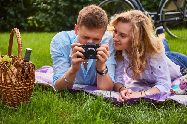 Amante joven pareja tomando fotos y relajándose en un picnic en un parque.
