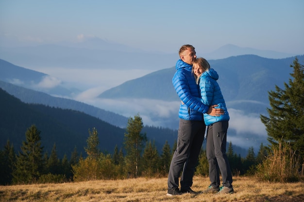 Amante pareja joven excursionistas abrazándose en las montañas