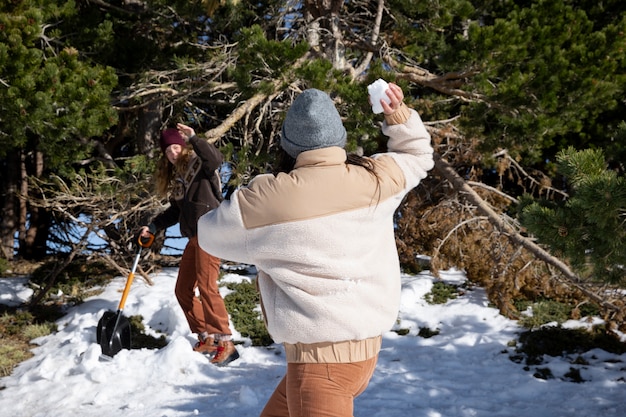 Amantes femeninos jugando y tirándose bolas de nieve durante el viaje de invierno