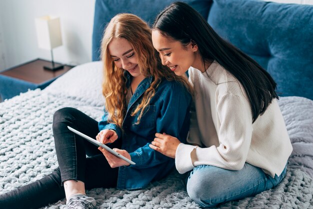 Amantes lesbianas alegres mirando tablet