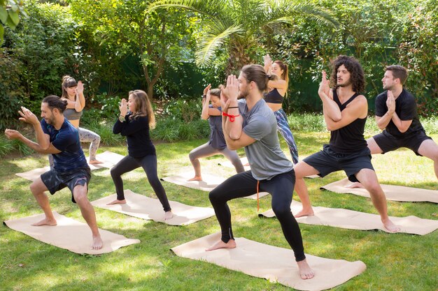 Amantes del yoga disfrutando de la práctica sobre hierba.
