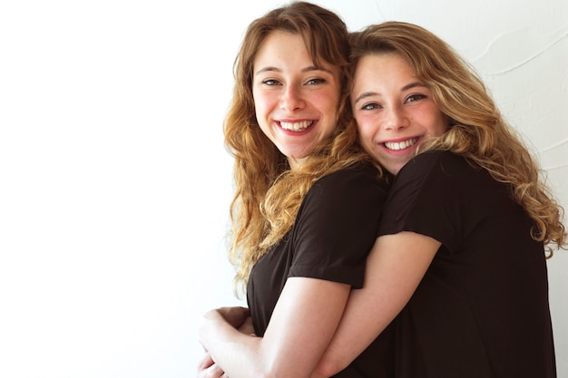 Foto gratuita amar a dos hermanas abrazando contra el telón de fondo blanco