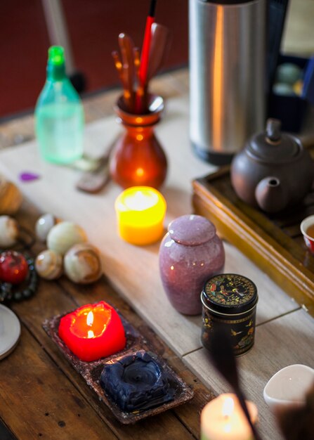 Amarillo; Velas encendidas azules y rojas con hervidor de té y canicas bolas de meditación en mesa de madera