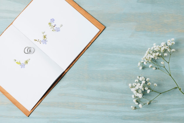 Foto gratuita ame el texto hecho con anillos de boda en un libro abierto con flor de gypsophila sobre fondo de madera