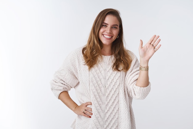 Amigable y atractiva compañera de trabajo saliente conociendo a los novatos sonriendo ampliamente saludando con la mano hola gesto de bienvenida a los miembros que expresan una vibra positiva