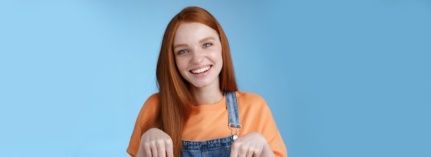 Foto gratuita amigable chica pelirroja feliz sonriendo animado sonrisa bonita apuntando hacia abajo dedos índice ofreciendo bueno