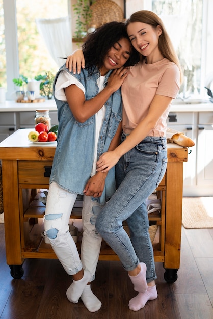 Amigas abrazándose y posando juntos en la cocina