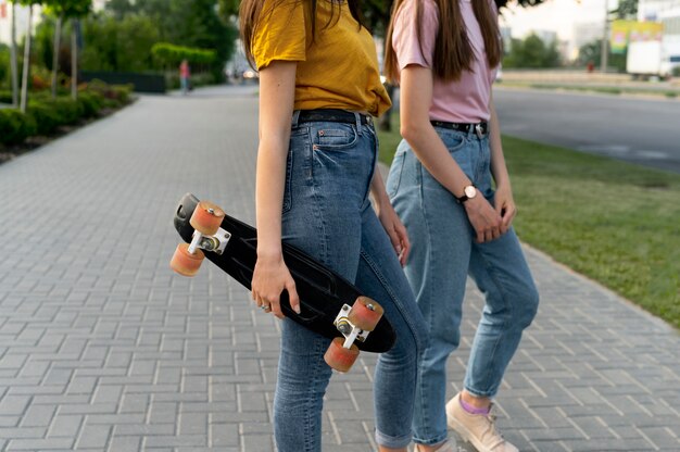 Amigas al aire libre en la ciudad con patineta