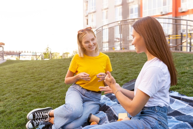 Foto gratuita amigas al aire libre utilizando lenguaje de señas