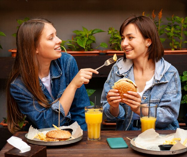 Amigas alimentándose mutuamente hamburguesas