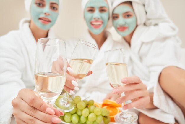 Amigas bebiendo vino en la cama