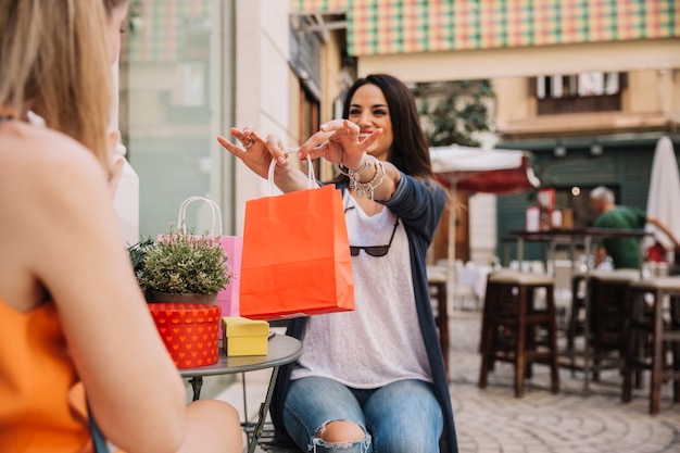 Amigas en cafetería con bolsa naranja