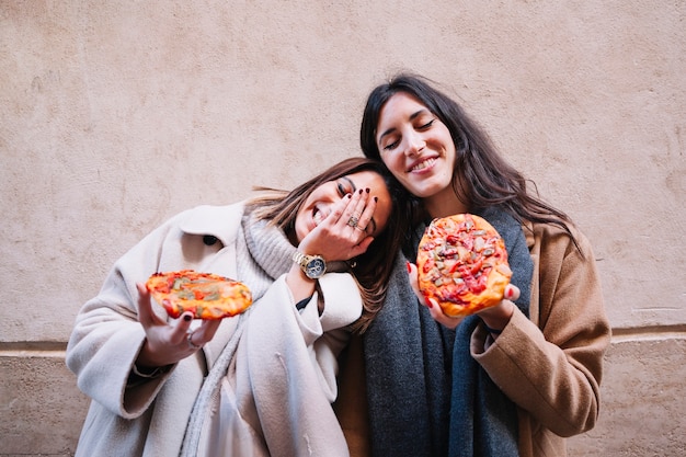 Amigas cariñosas con pizzas