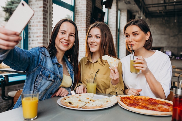 Foto gratuita amigas comiendo pizza en un bar a la hora del almuerzo